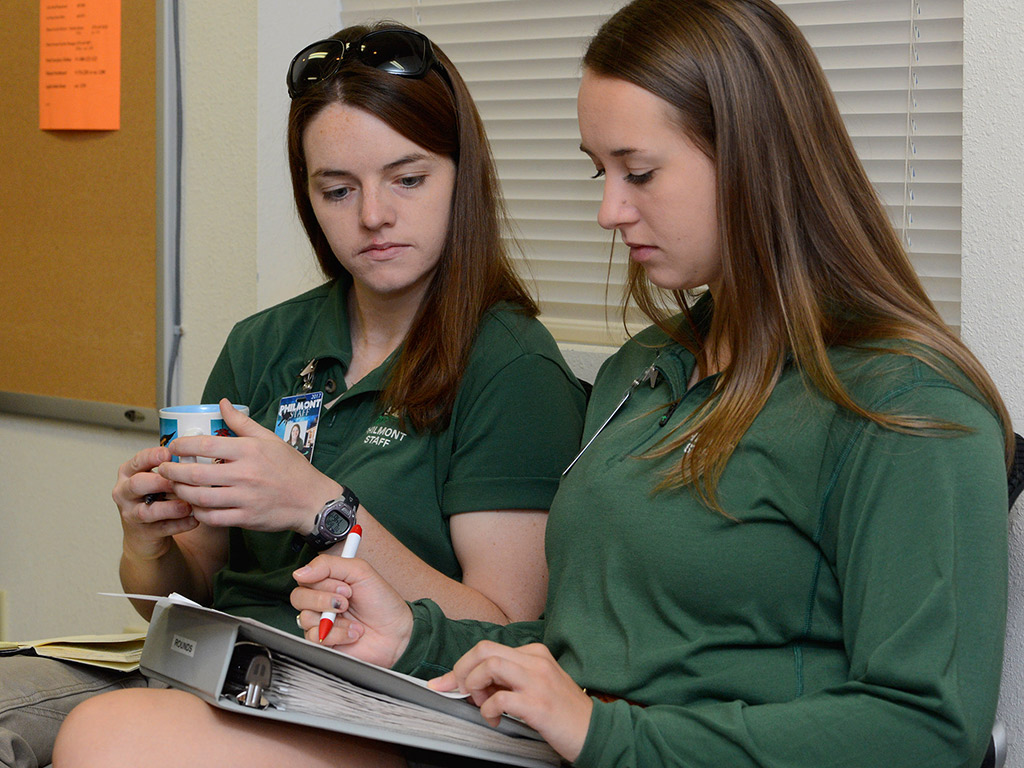 Two female students reviewing paperwork printed in a binder
